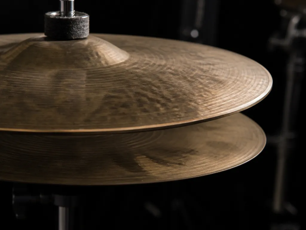 Extreme close-up macro photograph of a vintage drum kit hi-hat, two brass cymbals lit…